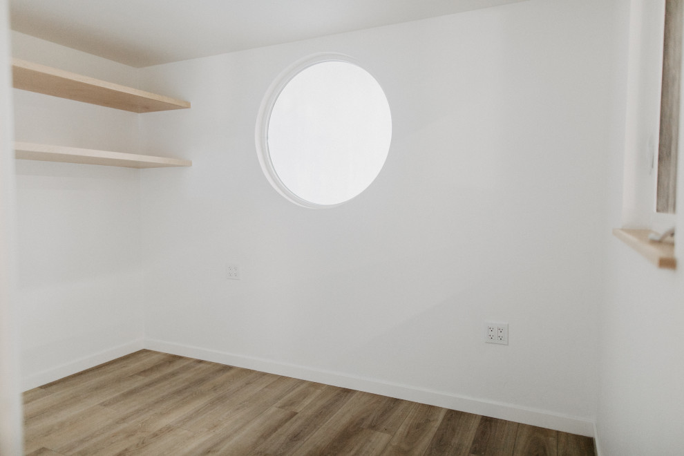 Idée de décoration pour une petite chambre mansardée ou avec mezzanine tradition avec un mur blanc, parquet clair et un plafond voûté.