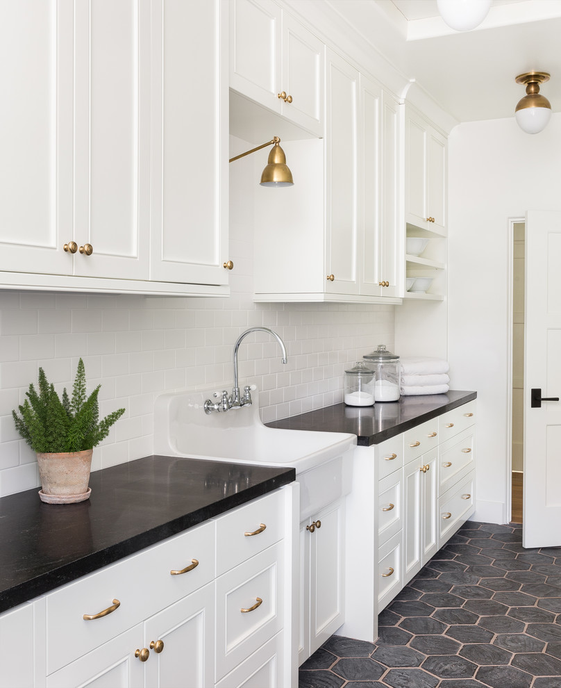 Design ideas for a transitional dedicated laundry room in Seattle with a farmhouse sink, recessed-panel cabinets, white cabinets, white walls, grey floor and black benchtop.