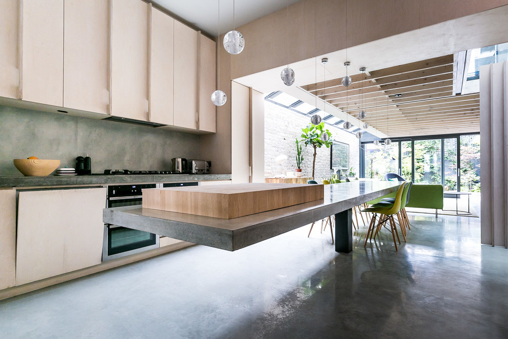 This is an example of a large contemporary single-wall kitchen in London with flat-panel cabinets, grey cabinets, concrete benchtops, grey splashback, stainless steel appliances, with island and grey floor.