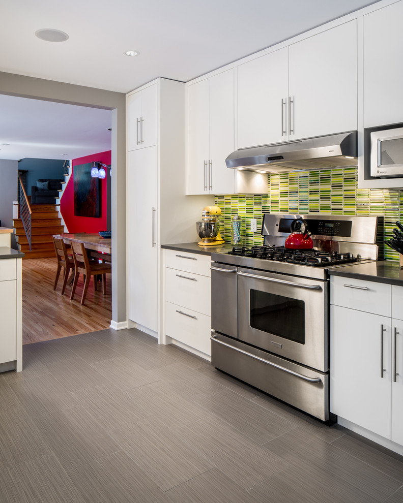 Design ideas for a contemporary kitchen in Minneapolis with flat-panel cabinets, white cabinets, solid surface benchtops, green splashback, mosaic tile splashback, stainless steel appliances, porcelain floors, no island and grey floor.