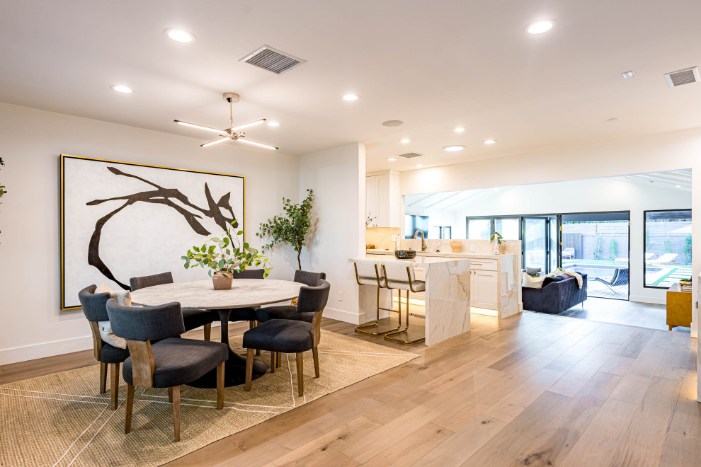 Esempio di una sala da pranzo aperta verso la cucina minimalista di medie dimensioni con pareti bianche, parquet chiaro, pavimento marrone e travi a vista