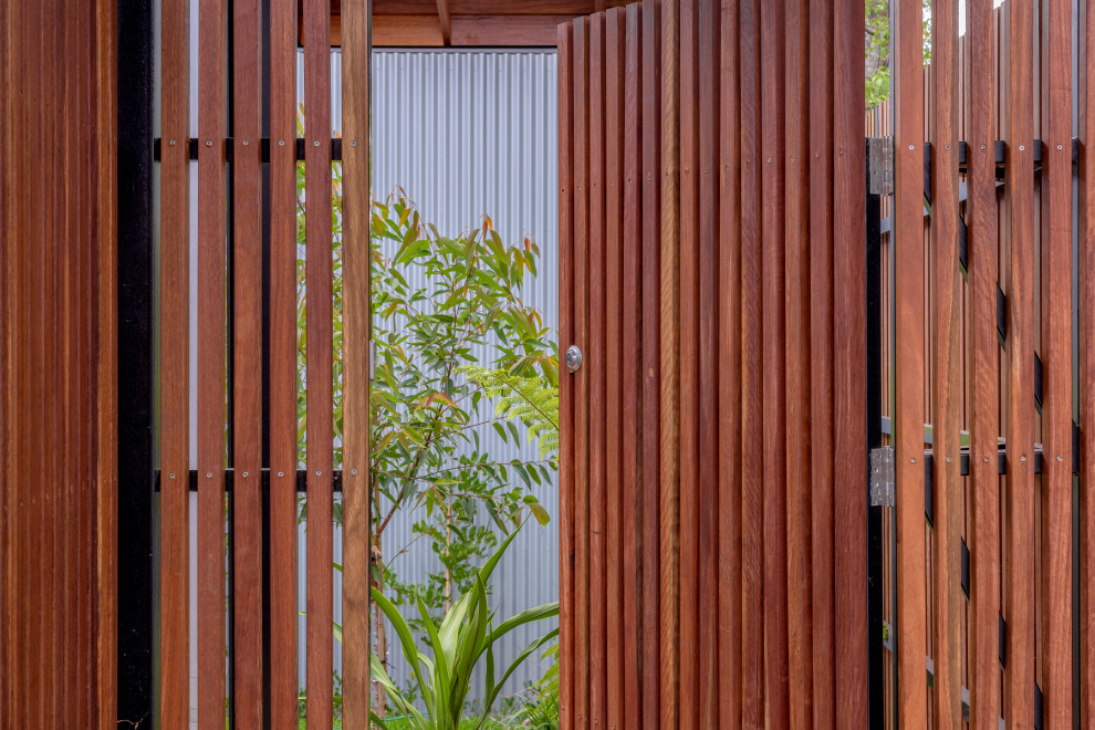 This is an example of an australian native industrial garden in Sydney with a wood fence.