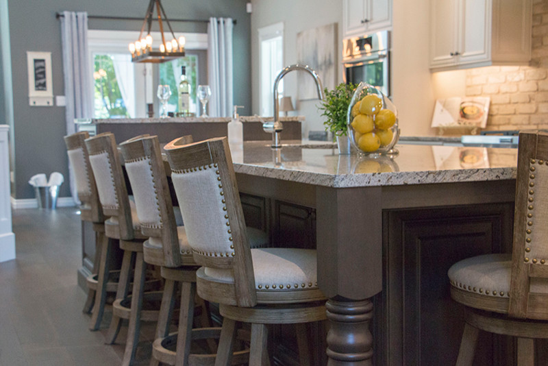 Large transitional l-shaped eat-in kitchen photo with a double-bowl sink, shaker cabinets, white cabinets, beige backsplash, stainless steel appliances and an island