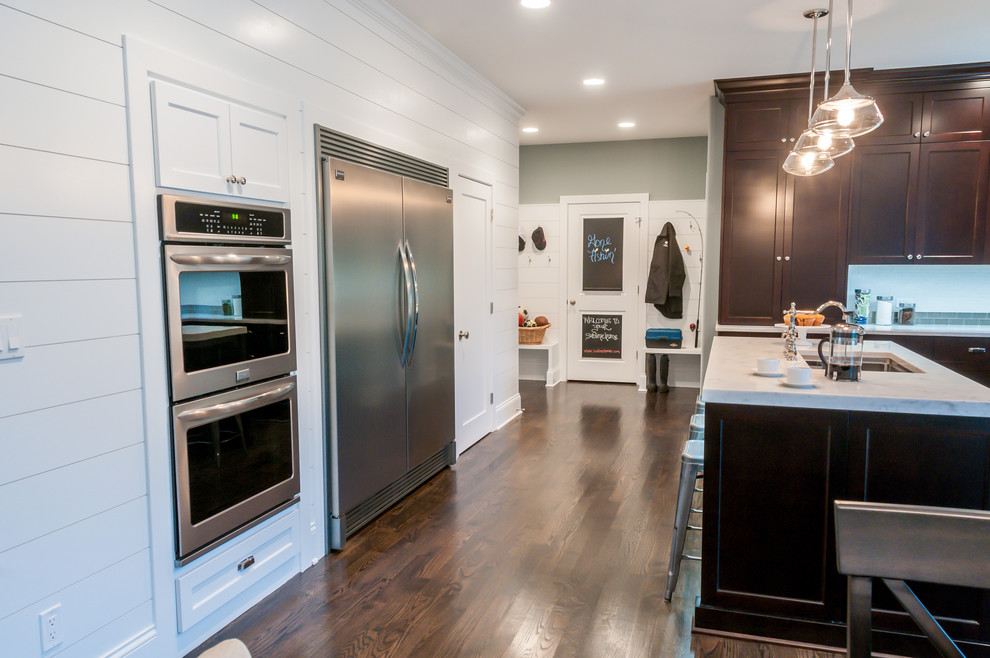 Example of a mid-sized transitional l-shaped dark wood floor eat-in kitchen design in Chicago with an undermount sink, recessed-panel cabinets, dark wood cabinets, quartzite countertops, white backsplash, ceramic backsplash, stainless steel appliances and an island