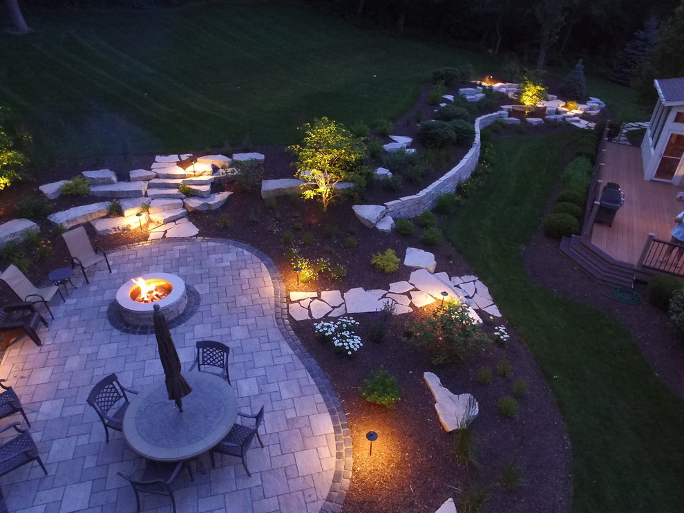 Design ideas for a large country backyard patio in Chicago with a fire feature, natural stone pavers and no cover.