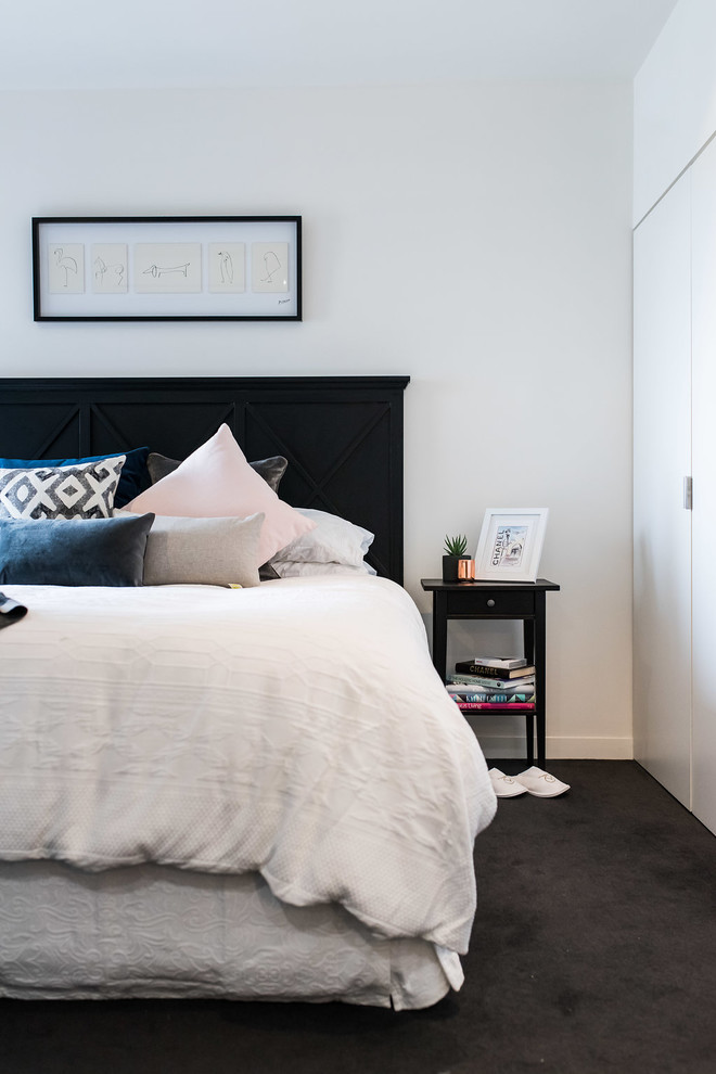 This is an example of a contemporary master bedroom in Melbourne with white walls, carpet and black floor.