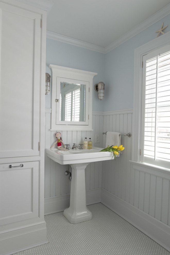 Traditional kids bathroom in New York with white cabinets, blue walls, mosaic tile floors and a pedestal sink.