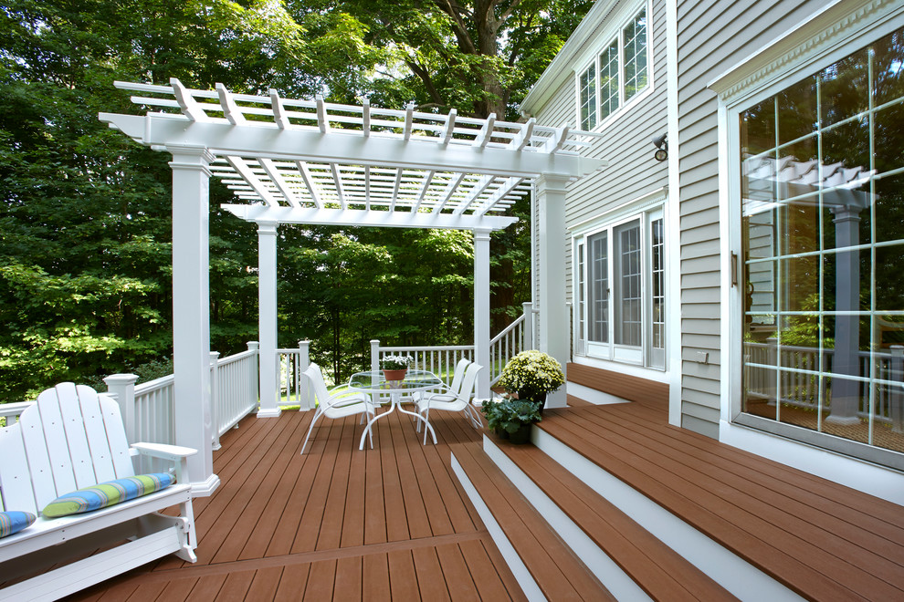 Large transitional backyard deck in New York with a pergola.