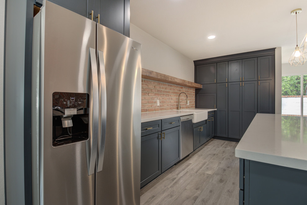 Inspiration for a mid-sized transitional u-shaped porcelain tile and gray floor eat-in kitchen remodel in Phoenix with a farmhouse sink, shaker cabinets, blue cabinets, quartz countertops, red backsplash, brick backsplash, stainless steel appliances, an island and white countertops