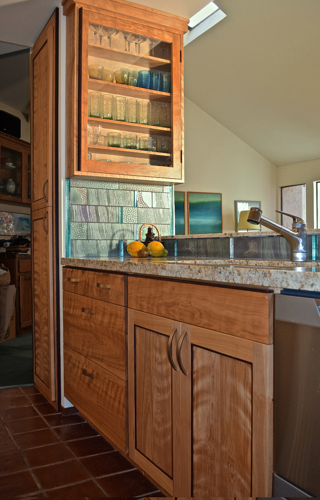 Mid-sized arts and crafts galley eat-in kitchen in San Francisco with granite benchtops, blue splashback, stainless steel appliances, ceramic floors, an undermount sink, flat-panel cabinets, medium wood cabinets, glass tile splashback and a peninsula.