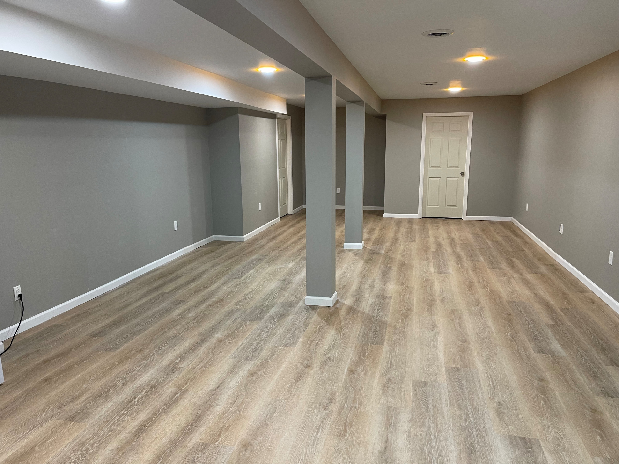 Large minimalist underground vinyl floor and brown floor basement photo in Cleveland with gray walls and no fireplace