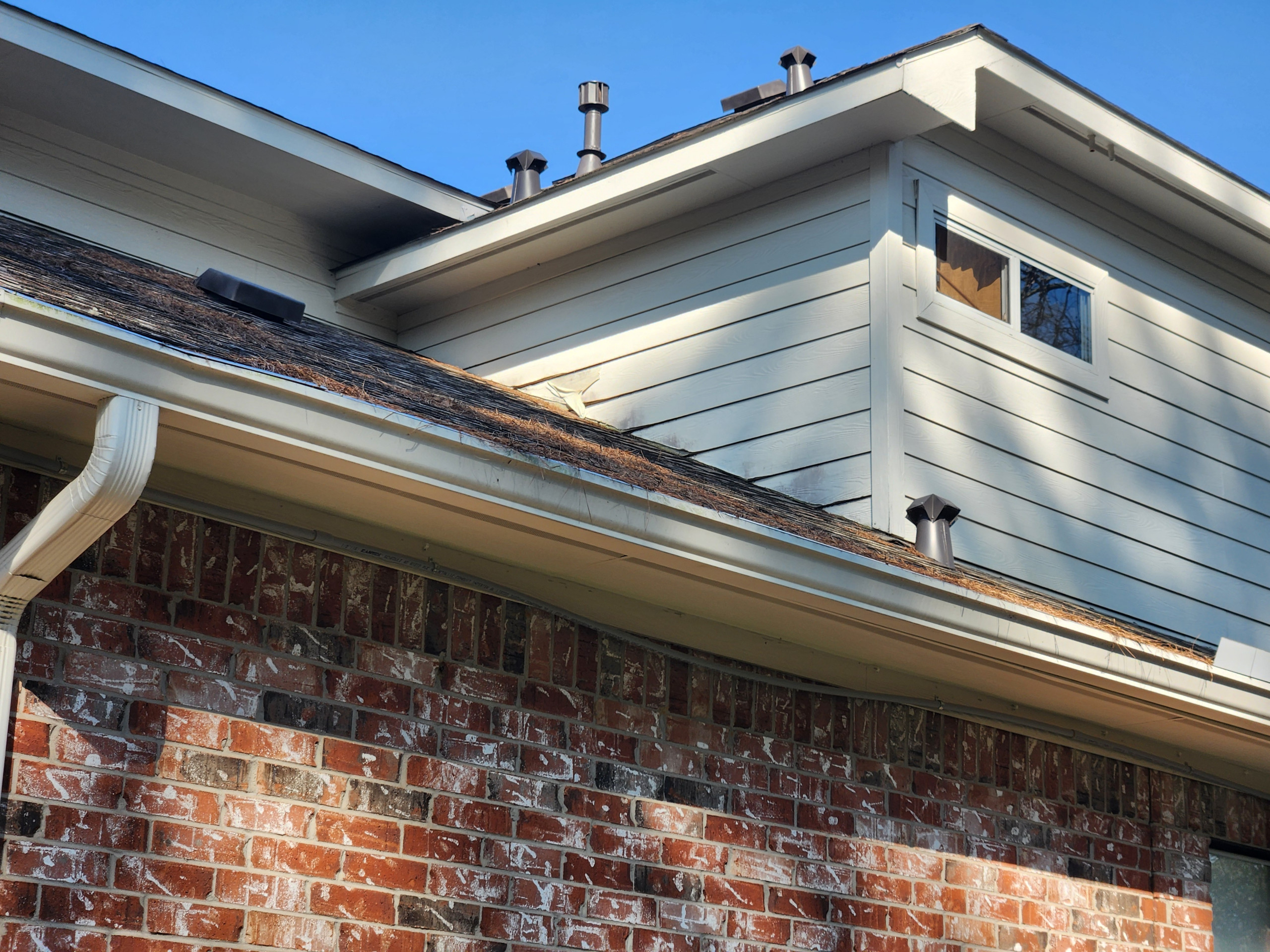 This project started with some non-Hardie fiber-cement siding planks delaminating above the roof lines. This was caused by the builder resting the siding on the roof, we cut all the siding on the hou