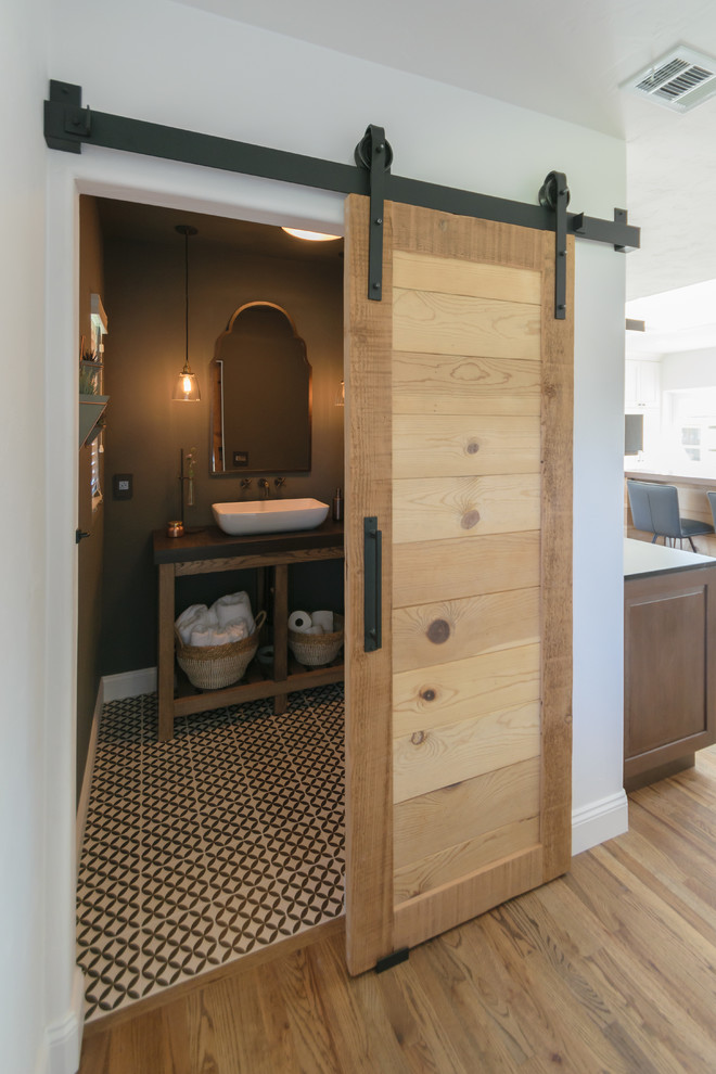 Inspiration for a huge transitional l-shaped medium tone wood floor and brown floor open concept kitchen remodel in San Francisco with a farmhouse sink, recessed-panel cabinets, white cabinets, soapstone countertops, white backsplash, stainless steel appliances, an island and black countertops