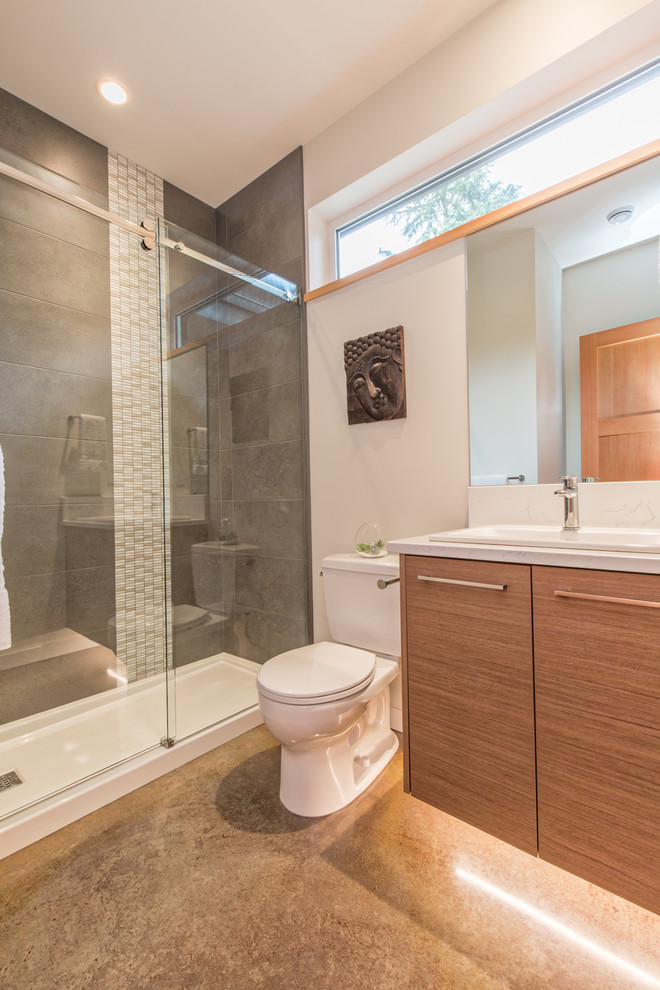 Design ideas for a mid-sized contemporary 3/4 bathroom in Vancouver with flat-panel cabinets, medium wood cabinets, an open shower, a two-piece toilet, gray tile, ceramic tile, white walls, concrete floors, a drop-in sink, quartzite benchtops, grey floor, a sliding shower screen and white benchtops.