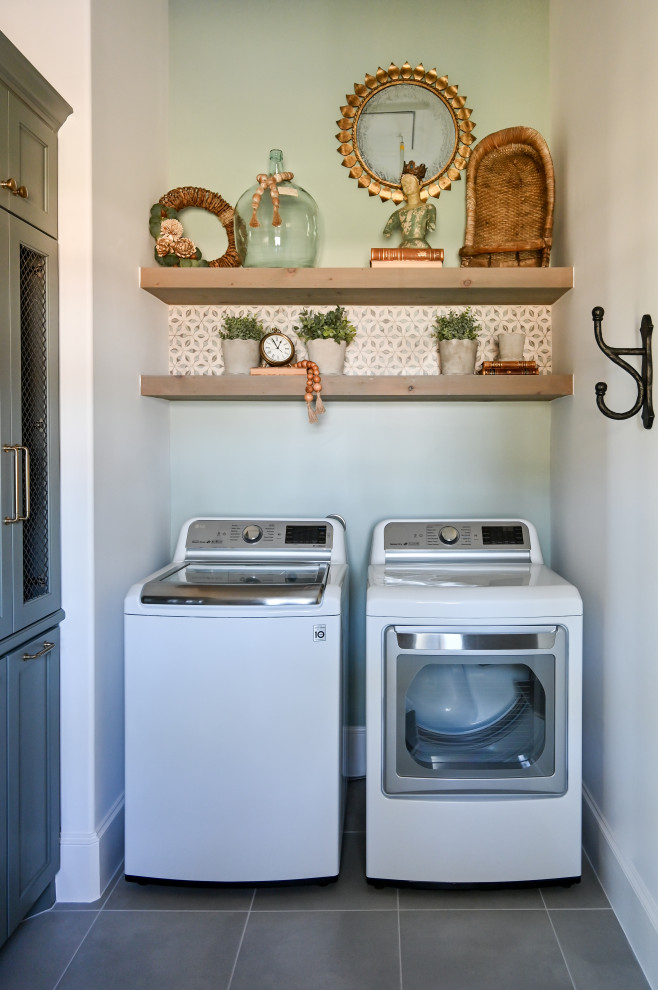Design ideas for a mid-sized l-shaped utility room in Houston with a farmhouse sink, recessed-panel cabinets, green cabinets, wood benchtops, multi-coloured splashback, mosaic tile splashback, green walls, porcelain floors, a side-by-side washer and dryer, grey floor and grey benchtop.