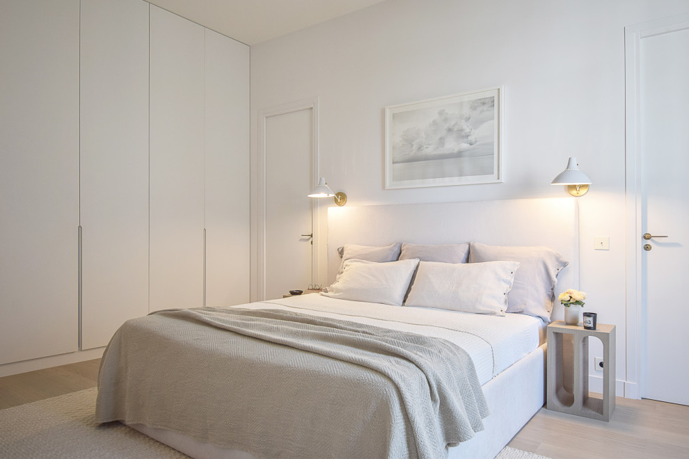 Photo of a large contemporary master bedroom in Paris with white walls and light hardwood flooring.