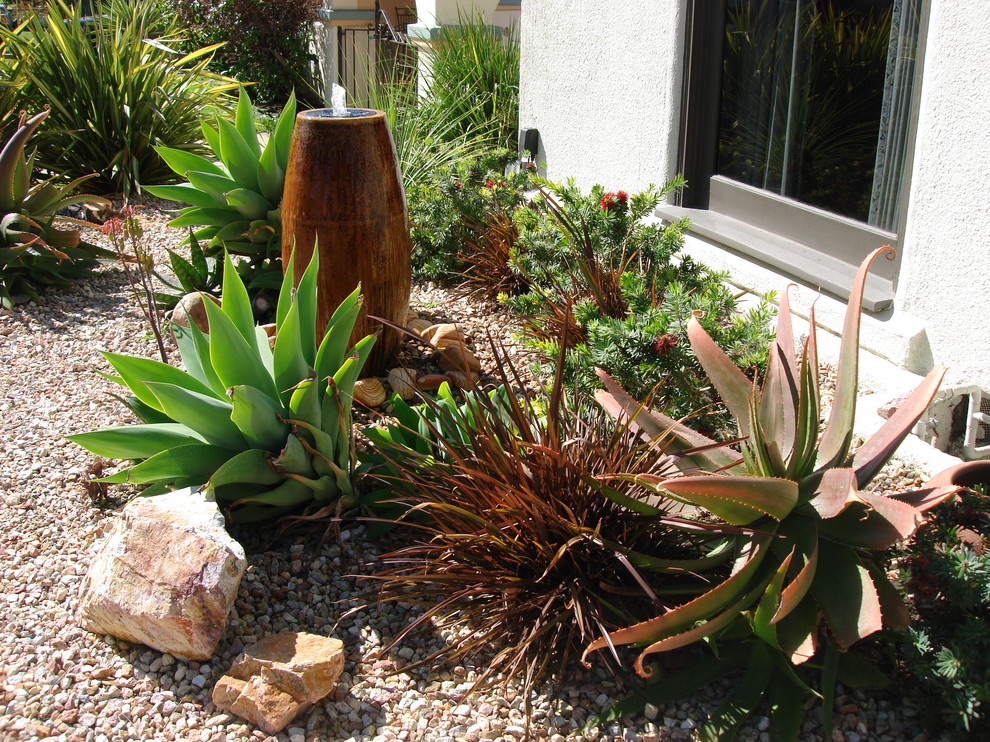 Photo of a large mediterranean front yard partial sun xeriscape in Los Angeles with brick pavers and a water feature.