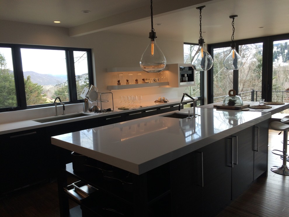 This is an example of a large modern u-shaped open plan kitchen in Salt Lake City with stainless steel appliances, with island, an undermount sink, flat-panel cabinets, black cabinets, quartz benchtops and medium hardwood floors.