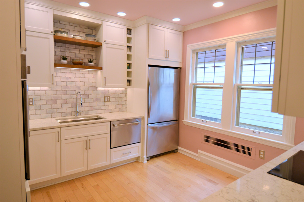 Small transitional light wood floor kitchen photo in Milwaukee with a single-bowl sink, shaker cabinets, white cabinets, quartzite countertops, ceramic backsplash and stainless steel appliances