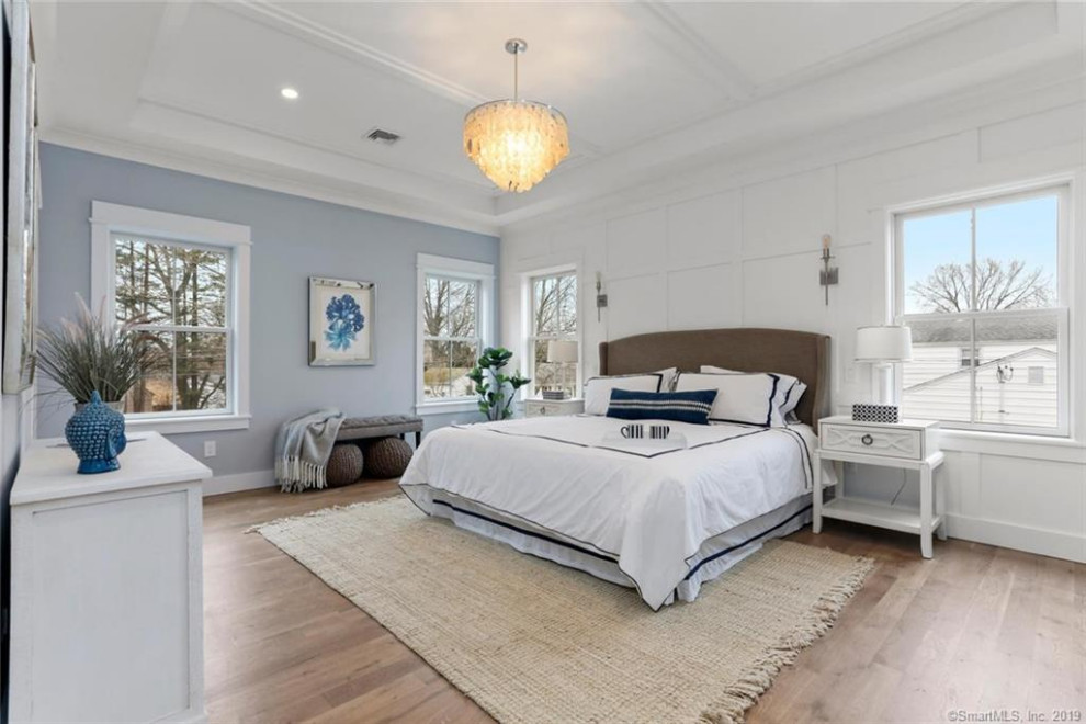 Design ideas for a large transitional master bedroom in New York with blue walls, medium hardwood floors, coffered and panelled walls.