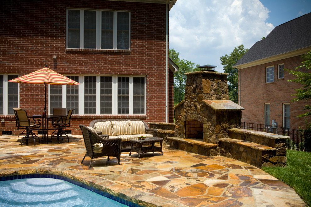Inspiration for a mid-sized traditional backyard custom-shaped pool in Charlotte with natural stone pavers.