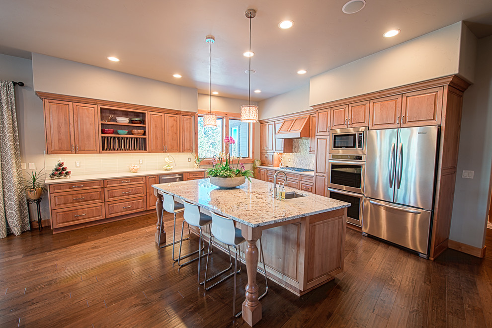 Large transitional l-shaped dark wood floor eat-in kitchen photo with raised-panel cabinets, light wood cabinets, granite countertops, white backsplash, an island, an undermount sink, glass tile backsplash and stainless steel appliances