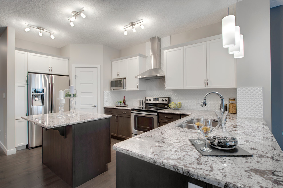 Inspiration for a mid-sized transitional l-shaped medium tone wood floor eat-in kitchen remodel in Edmonton with an undermount sink, shaker cabinets, white cabinets, granite countertops, white backsplash, porcelain backsplash, stainless steel appliances and an island