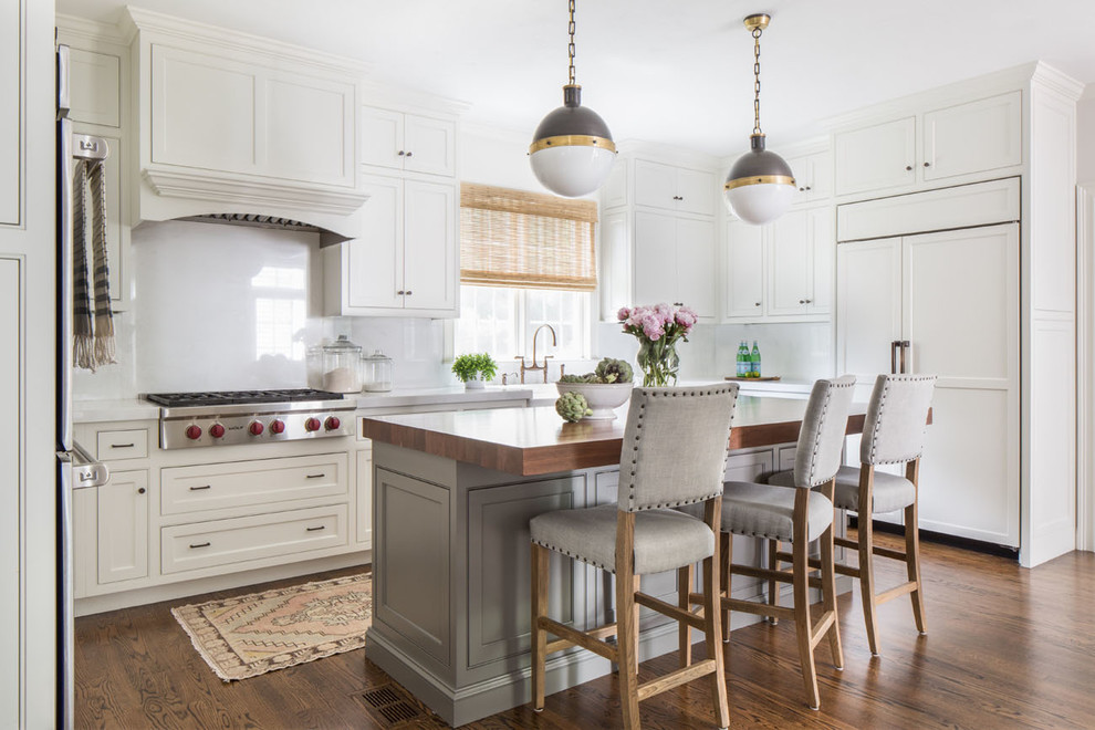 Example of a farmhouse dark wood floor kitchen design in Boston with a farmhouse sink, shaker cabinets, white cabinets, paneled appliances and an island
