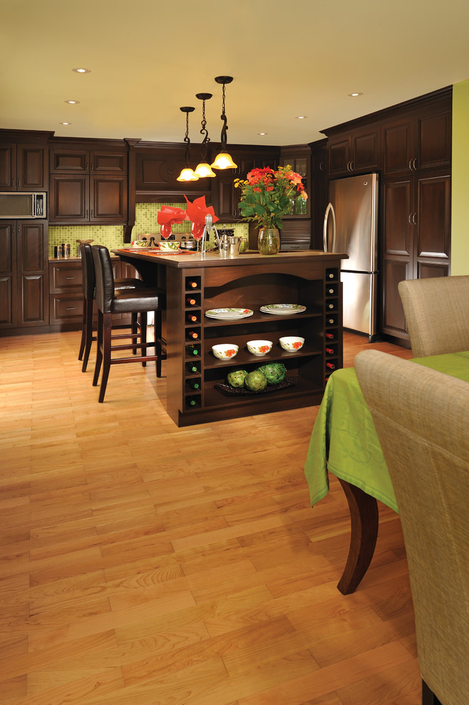Transitional l-shaped light wood floor eat-in kitchen photo with raised-panel cabinets, dark wood cabinets, green backsplash, stainless steel appliances and an island