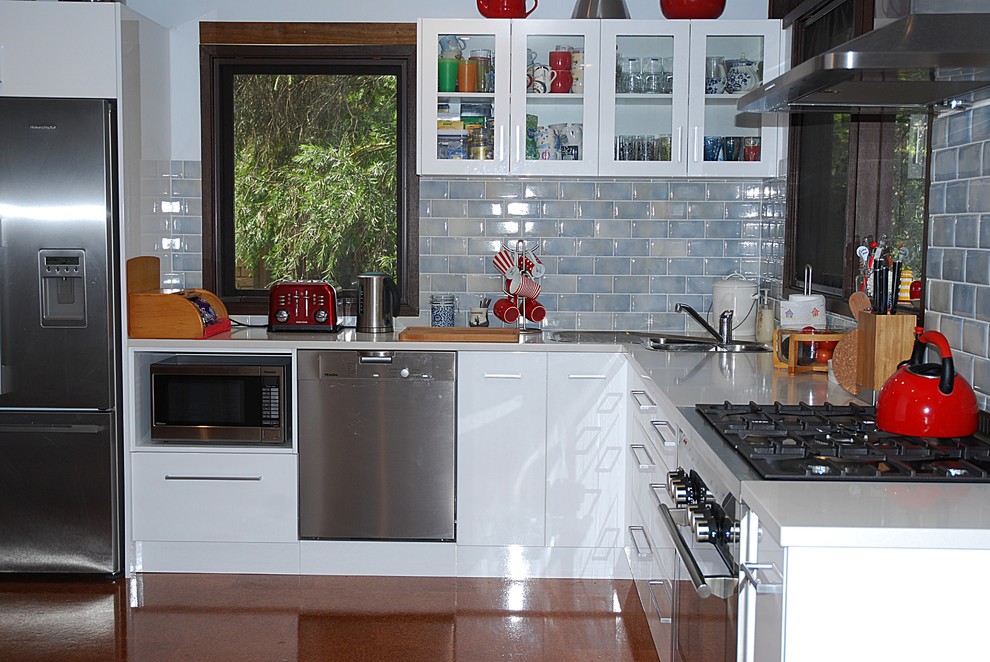 Inspiration for a mid-sized transitional l-shaped kitchen pantry in Sydney with a double-bowl sink, flat-panel cabinets, white cabinets, quartz benchtops, blue splashback, subway tile splashback, stainless steel appliances and cork floors.