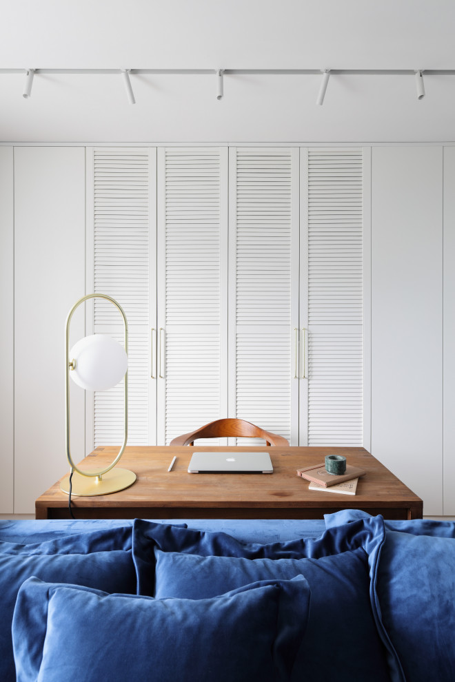 Modelo de despacho contemporáneo de tamaño medio con paredes blancas, suelo de madera en tonos medios, escritorio independiente y suelo marrón