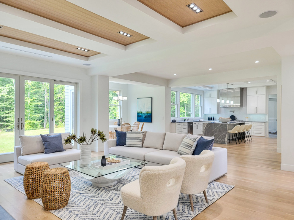 Photo of a large contemporary open concept family room in New York with white walls, light hardwood floors, a standard fireplace, a wall-mounted tv and coffered.