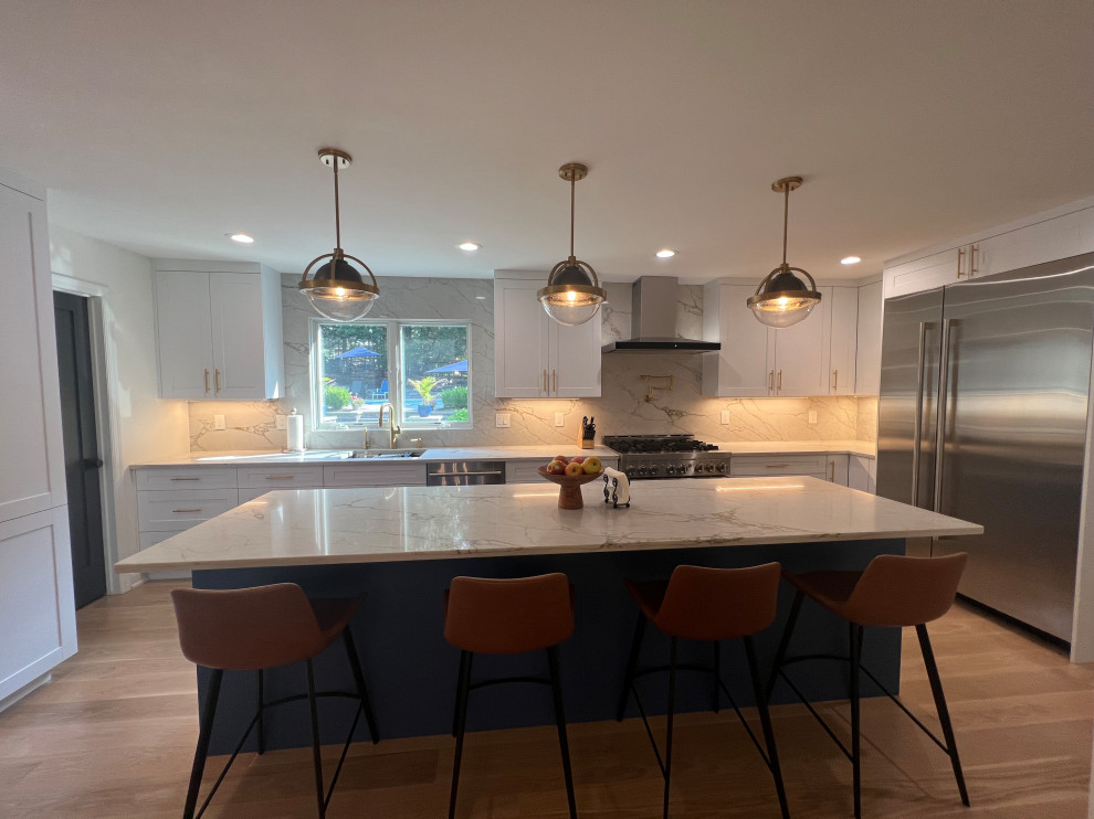 Inspiration for a mid-sized modern u-shaped eat-in kitchen in New York with an undermount sink, shaker cabinets, white cabinets, quartzite benchtops, beige splashback, engineered quartz splashback, stainless steel appliances, light hardwood floors, with island and beige benchtop.