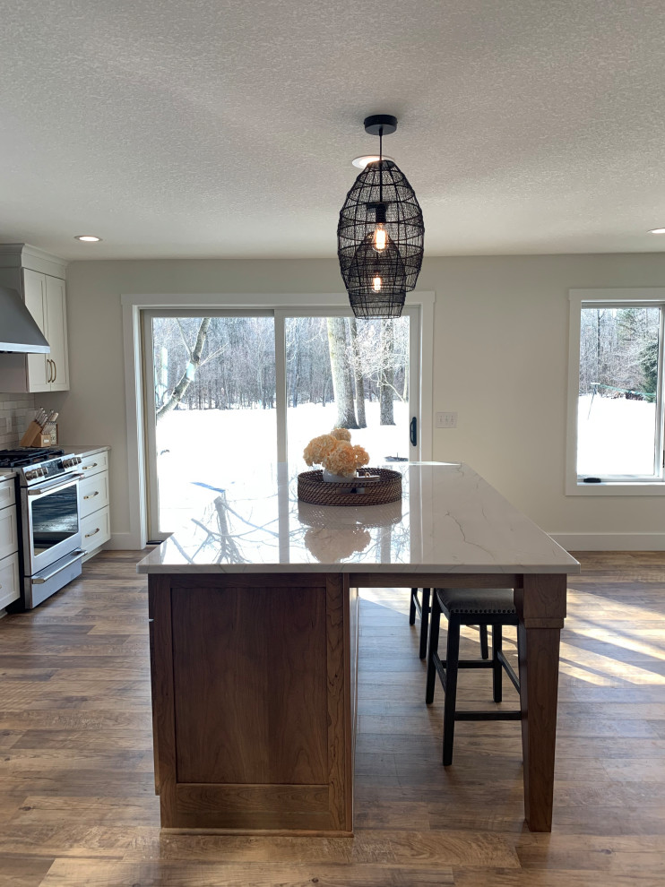 Eat-in kitchen - large transitional l-shaped vinyl floor and brown floor eat-in kitchen idea with an undermount sink, shaker cabinets, white cabinets, quartz countertops, stainless steel appliances, an island and gray countertops