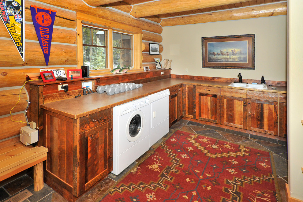 Example of a large mountain style l-shaped slate floor utility room design with a double-bowl sink, shaker cabinets, laminate countertops, a side-by-side washer/dryer, dark wood cabinets and gray walls