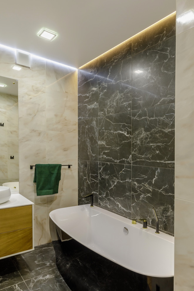 Пример оригинального дизайна: большая ванная комната в современном стиле с плоскими фасадами, отдельно стоящей ванной, угловым душем, черной плиткой, керамогранитной плиткой, бежевыми стенами, полом из керамогранита, душевой кабиной, подвесной раковиной, столешницей из искусственного камня, черным полом, душем с распашными дверями, белой столешницей, тумбой под две раковины и подвесной тумбой
