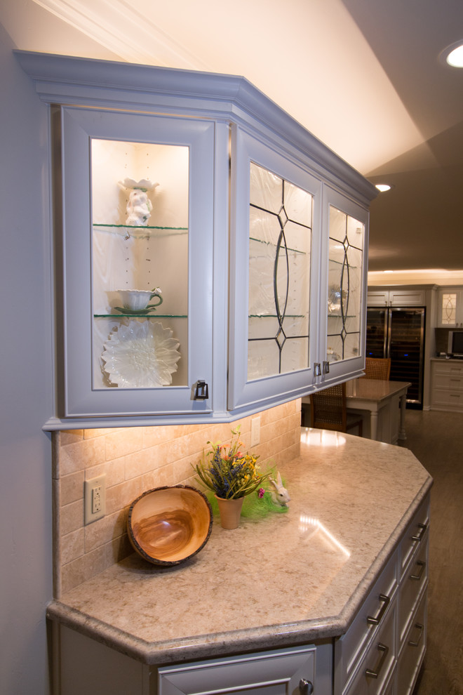 Huge transitional open concept kitchen photo with a farmhouse sink, recessed-panel cabinets, white cabinets, quartz countertops, beige backsplash, stone tile backsplash, stainless steel appliances and an island