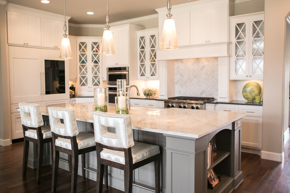 Eat-in kitchen - transitional l-shaped dark wood floor eat-in kitchen idea with an undermount sink, glass-front cabinets, white cabinets, marble countertops, gray backsplash, stone tile backsplash, stainless steel appliances and an island