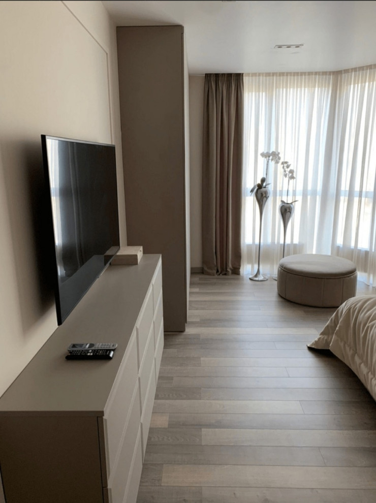 Свежая идея для дизайна: хозяйская спальня среднего размера с бежевыми стенами, полом из ламината, коричневым полом, обоями на стенах и телевизором без камина - отличное фото интерьера