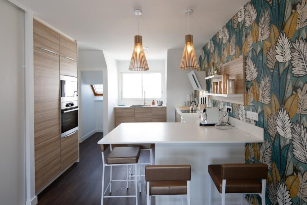 This is an example of a mid-sized contemporary u-shaped eat-in kitchen in Rennes with flat-panel cabinets, light wood cabinets, laminate benchtops, white splashback, stainless steel appliances, a peninsula and white benchtop.