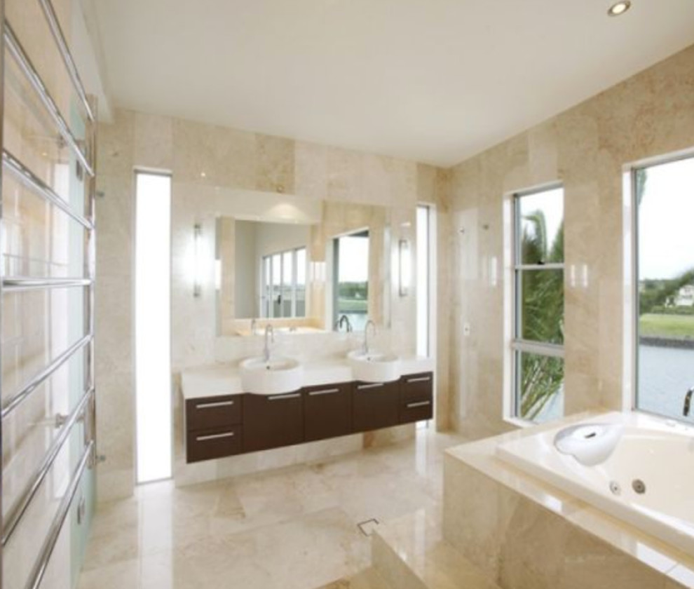 This is an example of a large contemporary master bathroom in Brisbane with furniture-like cabinets, brown cabinets, a drop-in tub, multi-coloured tile, multi-coloured walls, a drop-in sink, marble benchtops, multi-coloured floor, marble and marble floors.