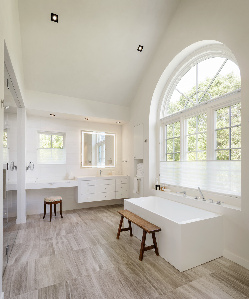 Inspiration for a transitional master bathroom in San Francisco with flat-panel cabinets, white cabinets, a freestanding tub, white walls and beige floor.