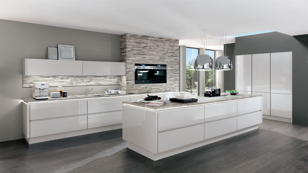 This is an example of a large contemporary u-shaped open plan kitchen in Hamburg with an integrated sink, flat-panel cabinets, beige cabinets, wood benchtops, beige splashback, glass sheet splashback, stainless steel appliances, cement tiles, a peninsula and grey floor.