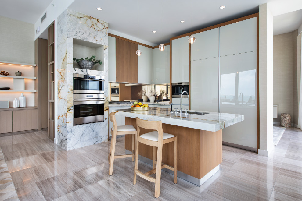 Contemporary l-shaped kitchen in Miami with an undermount sink, flat-panel cabinets, white cabinets, stainless steel appliances, with island, grey floor and white benchtop.
