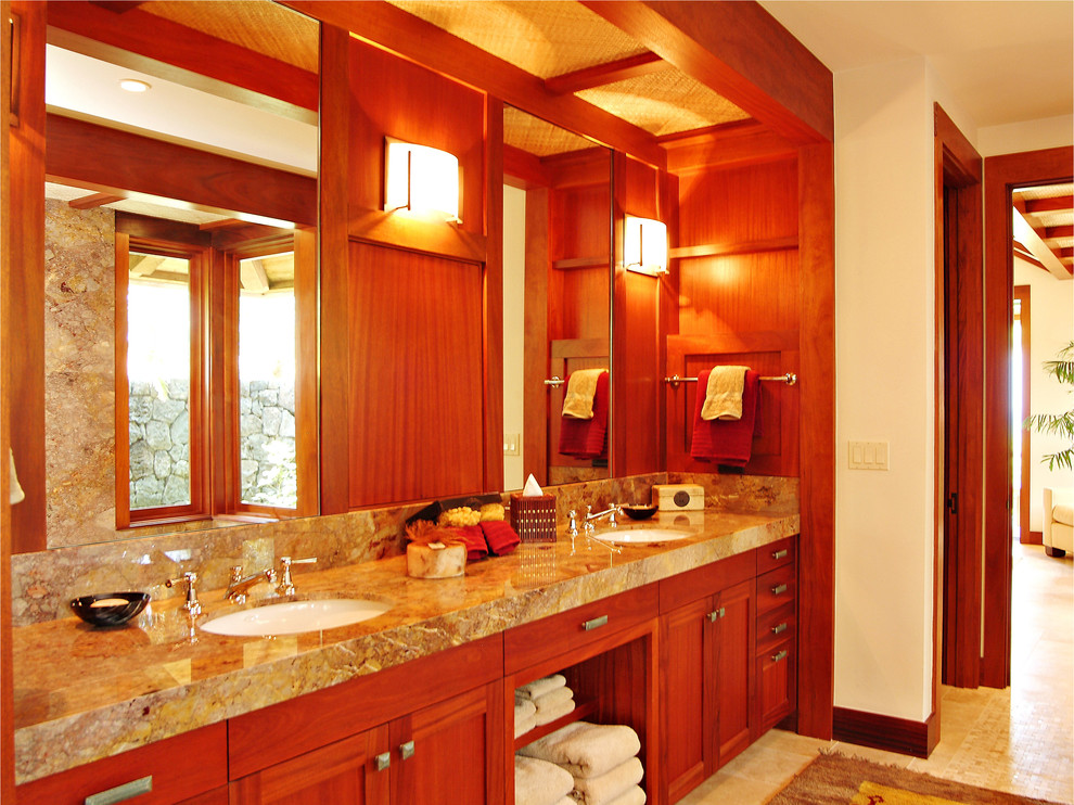 Photo of a mid-sized tropical master bathroom in Hawaii with shaker cabinets, medium wood cabinets, an undermount tub, an alcove shower, brown tile, stone slab, white walls, travertine floors, an undermount sink, beige floor, a hinged shower door and grey benchtops.