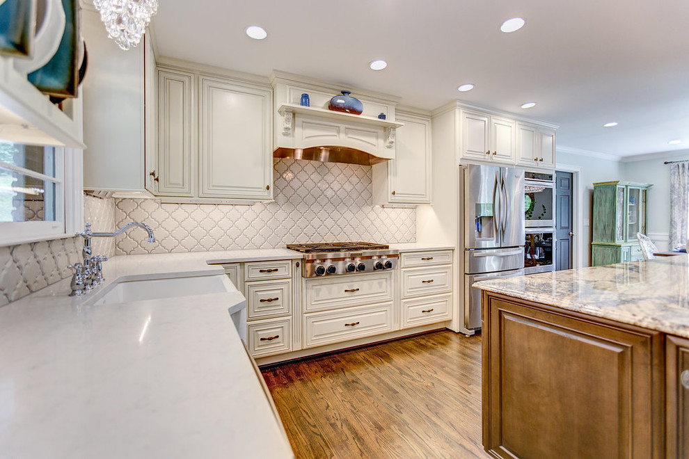 Large l-shaped medium tone wood floor open concept kitchen photo in Birmingham with a farmhouse sink, raised-panel cabinets, medium tone wood cabinets, granite countertops, white backsplash, ceramic backsplash, stainless steel appliances and an island