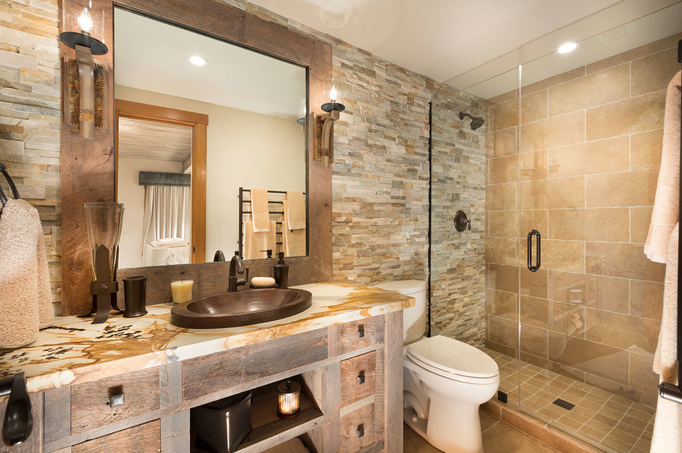 This is an example of a mid-sized eclectic bathroom in Other with furniture-like cabinets, distressed cabinets, a two-piece toilet, brown tile, brown walls, a vessel sink, granite benchtops, a hinged shower door, travertine, travertine floors and brown floor.