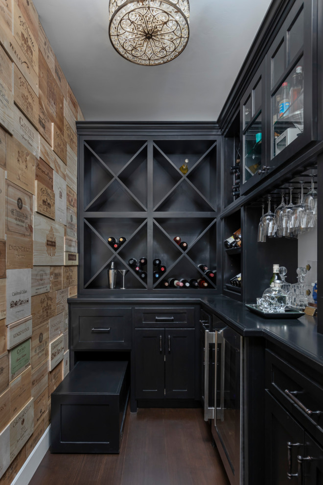 Inspiration for a beach style l-shaped home bar in Los Angeles with black cabinets, dark hardwood floors, brown floor and black benchtop.