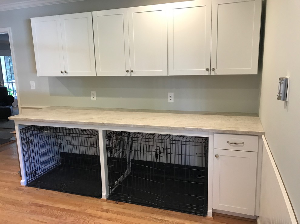 This is an example of a traditional utility room in Baltimore with a farmhouse sink, recessed-panel cabinets, white cabinets, quartzite benchtops, light hardwood floors and a side-by-side washer and dryer.
