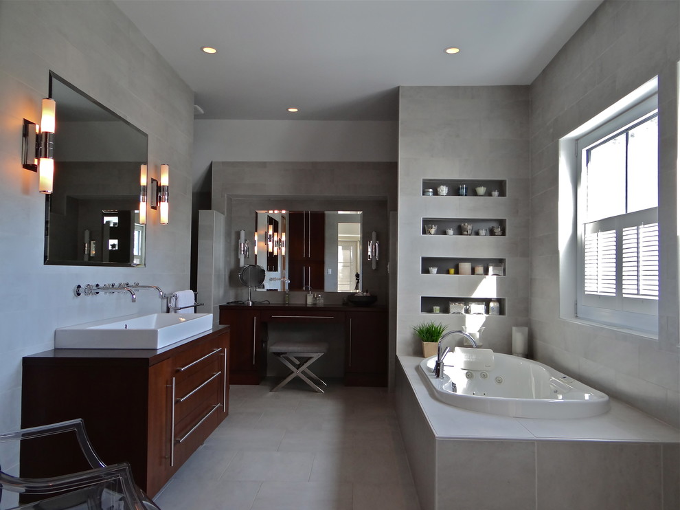 This is an example of a mid-sized industrial master bathroom in Calgary with flat-panel cabinets, dark wood cabinets, a drop-in tub, gray tile, cement tile, grey walls, cement tiles, a trough sink and wood benchtops.